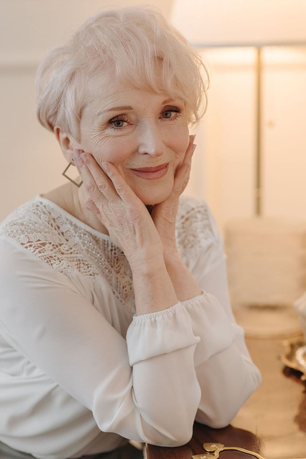 Woman in her sixties with white hair resting her face in her hands