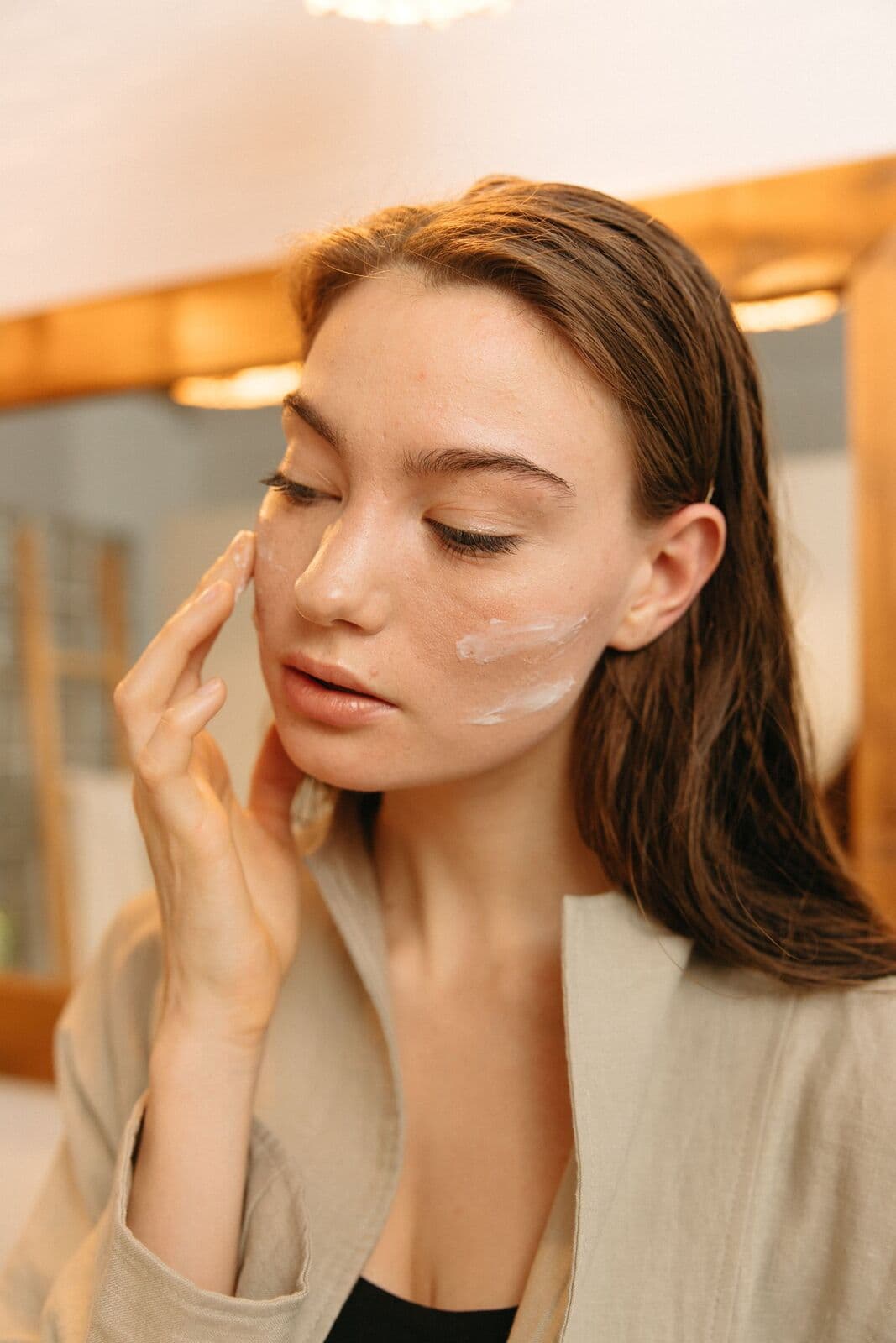 Woman massaging cleanser into her cheek at a mirror