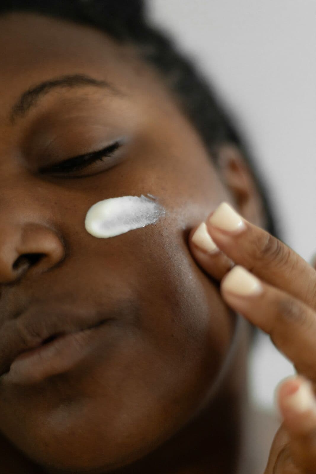 Woman pressing a dab of cream into her cheek