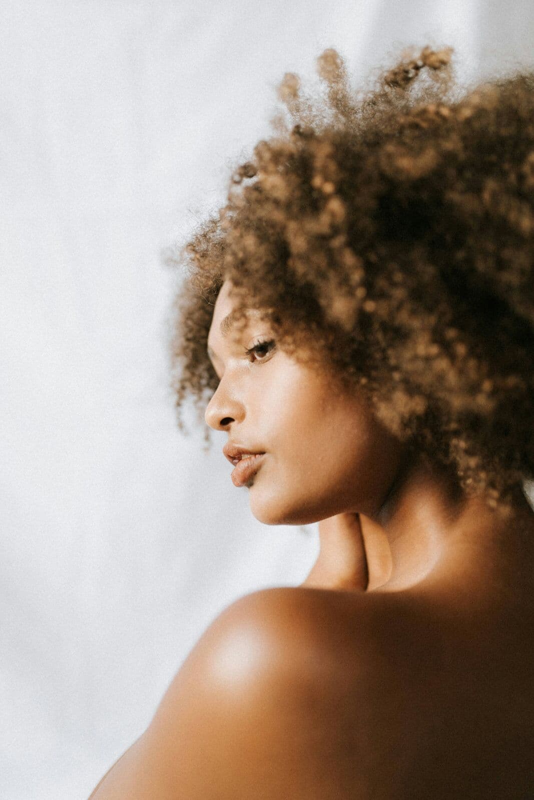Profile of a woman with natural curls and bare, even skin