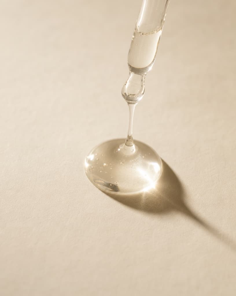 A thick clear drop falling from a glass rod