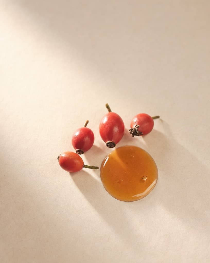 Red rosehips beside a pool of orange oil