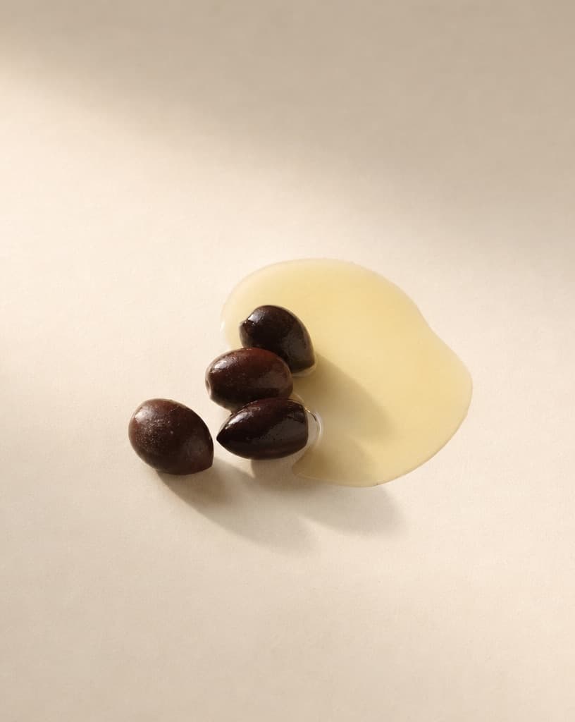 Ripe olives beside a thin pool of clear oil