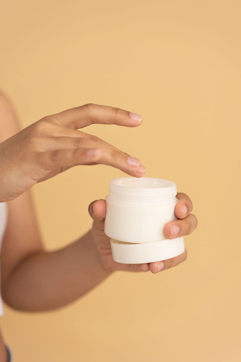 Hand lifting the lid from a jar of Barrier Cream