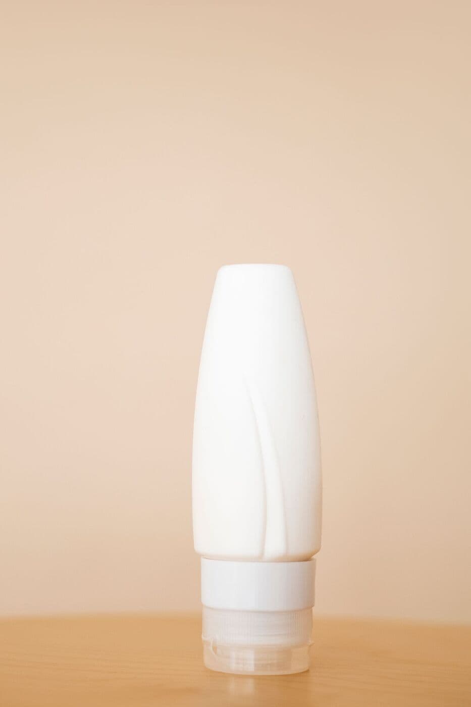 White tube of Milk Cleanser on a peach background