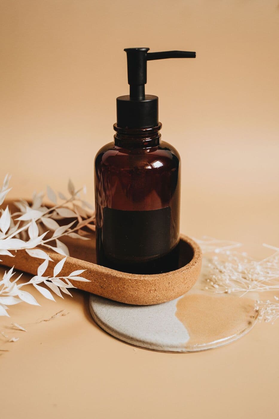 Amber glass pump bottle of Oil Cleanser on a ceramic tray