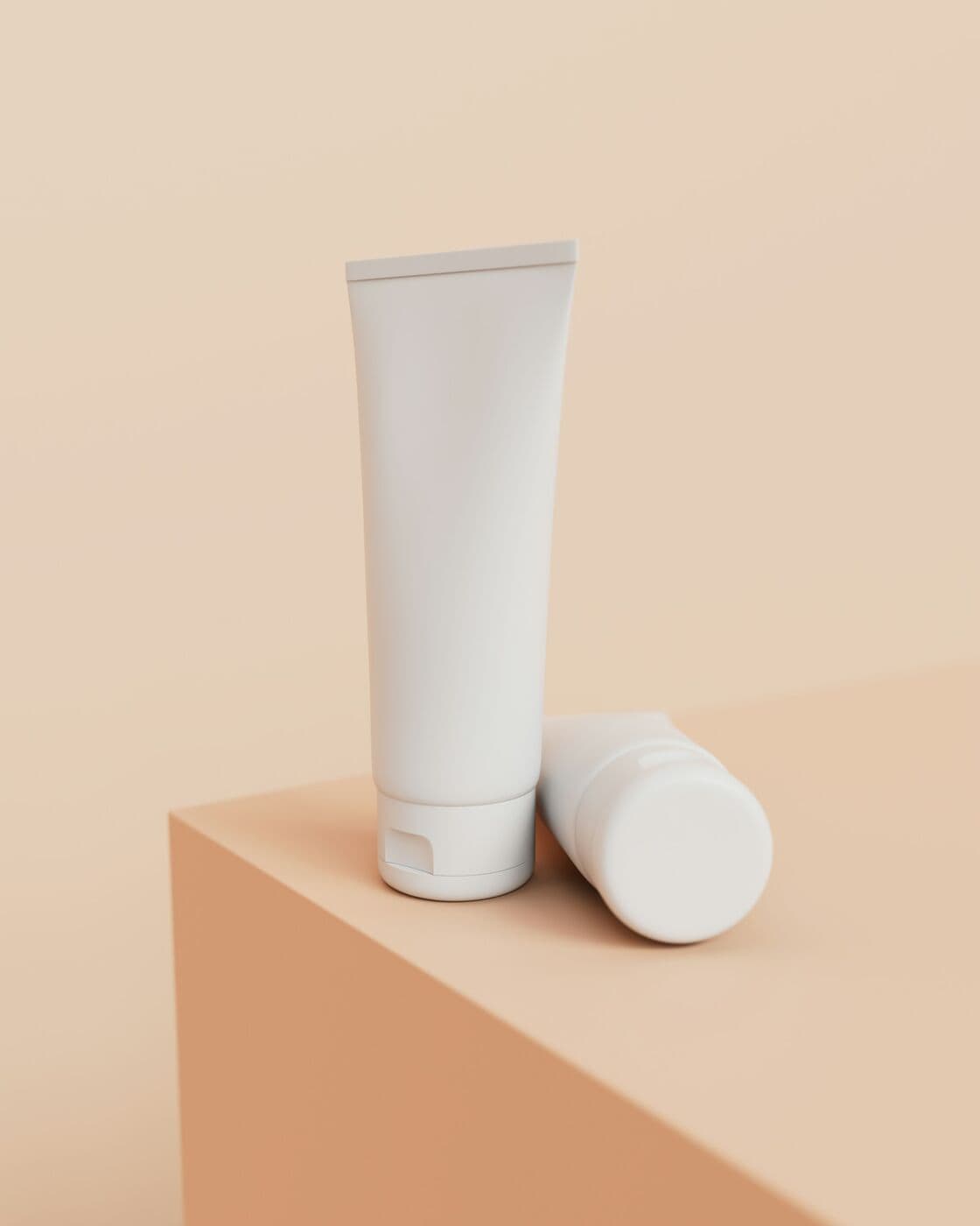 White tube of Tinted SPF 30 standing on a peach plinth