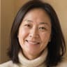 Woman in her forties with shoulder-length dark hair smiling in a cream knit turtleneck